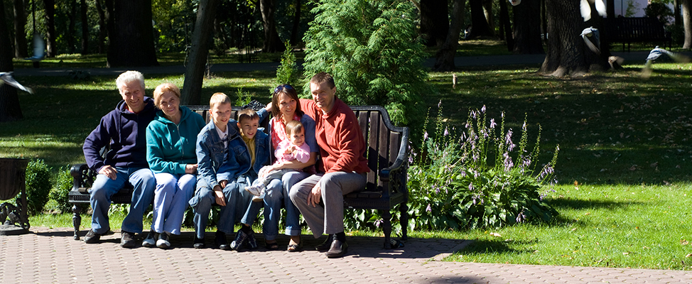 Banner image of multi-generational family sitting on a park bench.