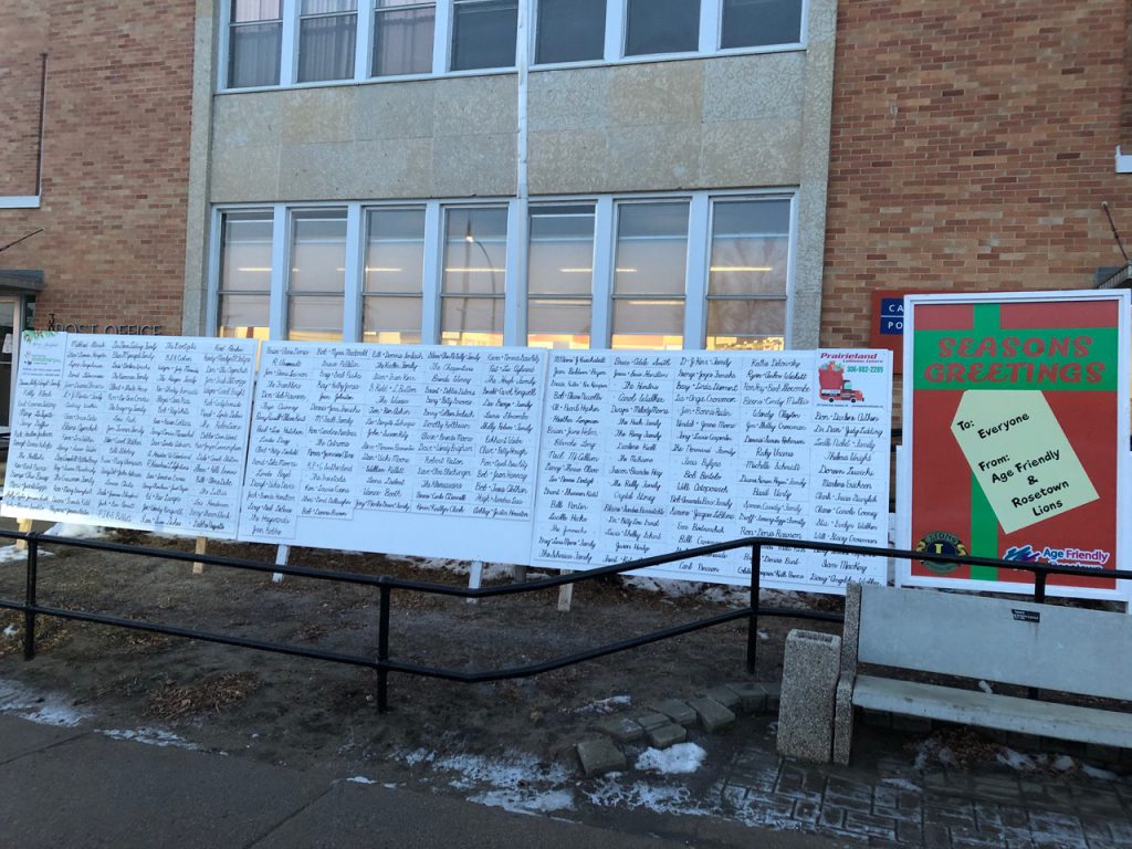 Image of Age-Friendly Rosetown and Rosetown Lions' Seasons Greetings board outside a public building. The board is filled with names.