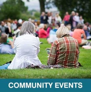 Thumbnail Photo of two older women with their backs to us, sitting on a lawn with many other people. Caption is Community Events.