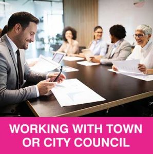 Thumbnail photo of ethnically and age diverse people meeting around a board table. Caption is Working with Town or City Council.